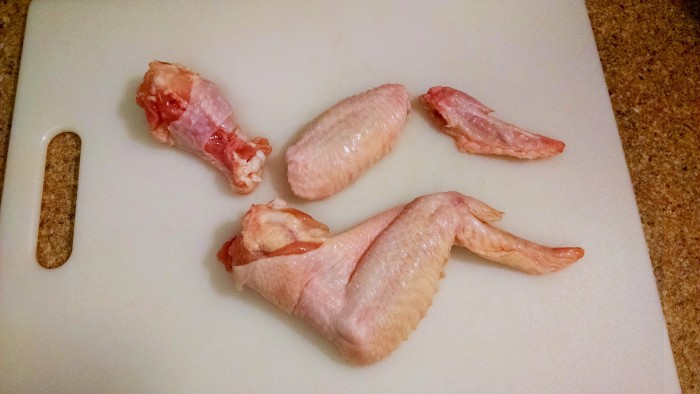 The wings have three parts: the drumette, wingette, and wing tip.  To separate, find the joint with your fingers and cut through with a chef's knife.  Discard the wing tips or save for chicken stock!
